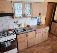 Küche in einer Einzimmerwohnung mit Holzschränken und einem Gasherd.