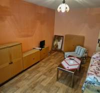 Ein Zimmer mit Holzmöbeln und einem Sessel in einer Einzimmerwohnung.