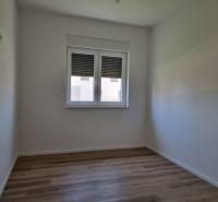 Ein Zimmer einer 4-Zimmer-Wohnung mit Holzboden, weißen Wänden und einem Fenster.