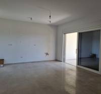 Geräumiges Interieur einer neuen 4-Zimmer-Wohnung mit großen Glastüren und Fliesenboden.