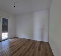 Ein leerer Raum mit Holzboden und Balkontüren in einer Vierzimmerwohnung.