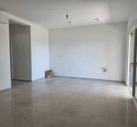 Geräumiges Wohnzimmer in einer 4-Zimmer-Wohnung mit Keramikboden und weißen Wänden.