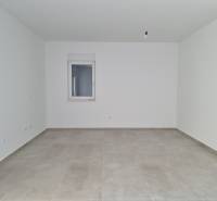 Ein leerer Raum in einer 4-Zimmer-Wohnung mit Fliesenboden und Fenster.