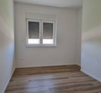Ein Zimmer mit Holzboden und Fenster in einer 4-Zimmer-Wohnung.