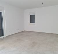 Leerer Raum mit hellen Wänden und Fliesen in einer 4-Zimmer-Wohnung.