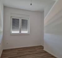 Innenraum einer 4-Zimmer-Wohnung mit Holzboden und heruntergelassenen Jalousien am Fenster.