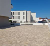 Parkplatz bei einer 4-Zimmer-Wohnung in der Stadt Vodice mit befestigter Oberfläche und klarer Architektur.