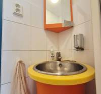 Ein orangefarbenes Waschbecken mit einem runden gelben Rand, ein Spiegel und ein Handtuchhalter.
