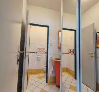 Toilette mit weißen und gelben Fliesen und einem orangefarbenen Waschbecken in Geschäftsräumen.