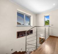 Holztreppe mit Metallgeländer, Bücherregal und Fenster in einem Einfamilienhaus.