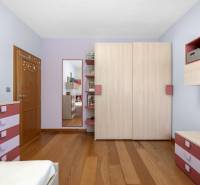 Kinderzimmer in einem Einfamilienhaus mit rosa und lila Kommoden, einem Spiegel und Holzboden.