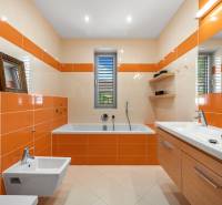 Ein Badezimmer in einem Einfamilienhaus mit orange-beigen Fliesen, einer Badewanne, einem Waschbecken und einem Bidet.