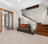 Einfamilienhaus mit Holztreppe, Glas und Sofa mit Kissen.