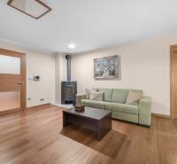 Wohnzimmer mit Holzboden, grüner Couch und Kachelkamin in einem Einfamilienhaus.