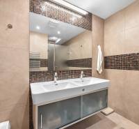 Badezimmer mit Doppelwaschbecken, braunen Fliesen und Spiegel in einem Einfamilienhaus.