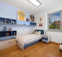 Kinderzimmer in einem Einfamilienhaus mit Bett, Regalen, Bildern und moderner Ausstattung.