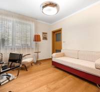 Ein Zimmer in einem Einfamilienhaus mit einem Sofa, Sesseln, einer Lampe und Holzboden.