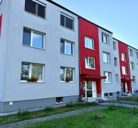 Ein Wohnblock auf dem Wohnsiedlung in Jablonica mit grauer Fassade und roten Elementen.
