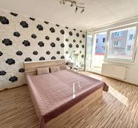 Schlafzimmer in einer 2-Zimmer-Wohnung mit gemusterten Tapeten und einem Doppelbett.