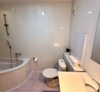 Badezimmer in einer 2-Zimmer-Wohnung mit Badewanne, Waschbecken und Toilette, helle Fliesen.
