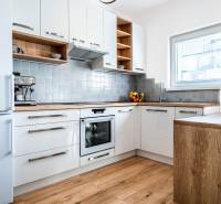 Küche in einer 2-Zimmer-Wohnung mit weißen Schränken und Holzelementen.