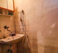Badezimmer in der Hütte mit Waschbecken, Holzdecke und kleinem Fenster.