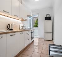 Küche mit weißen Schränken, Geräten und einem Fenster in einer Zweizimmerwohnung.