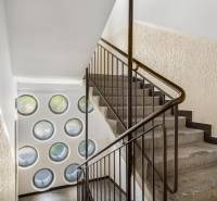 Treppe mit Geländer, runde Fenster, strukturierte Wände, räumliche Anordnung.
