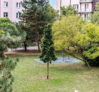 Park in Bratislava auf den Tschechoslowakischen Fallschirmjägern mit einer Bank und Grünflächen, umgeben von Wohnhäusern.