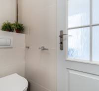 Badezimmer einer Zweizimmerwohnung mit Toilette, Keramikfliesen und Glastüren.