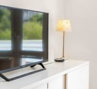 Ein Fernseher und eine Lampe auf einer weißen Kommode in einer Zweizimmerwohnung.
