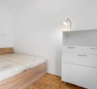 Schlafzimmer mit Bett und Kommode in einer 2-Zimmer-Wohnung, Boden mit Holzdekor.