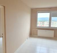 Ein leeres Zimmer in einer 3-Zimmer-Wohnung, mit einem Heizkörper unter einem großen Fenster.