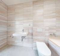 Badezimmer in einem Einfamilienhaus mit beigen Fliesen, Waschbecken und Toilette.