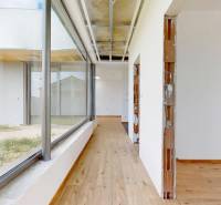 Einfacher Flur mit Holzboden und großen Fenstern in einem Einfamilienhaus.