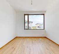 Ein leerer Raum mit Holzboden und einem großen Fenster in einem Einfamilienhaus.