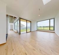 Ein geräumiges Zimmer eines Einfamilienhauses mit Holzboden und großen Fenstern.