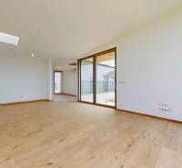 Ein geräumiges Zimmer mit großen Fenstern und Holzboden in einem Einfamilienhaus.