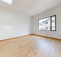 Leerer, heller Raum mit Holzboden und großem Fenster in einem Einfamilienhaus.