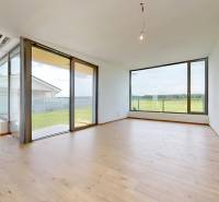 Ein geräumiges Wohnzimmer mit Holzboden und großen Fenstern im Einfamilienhaus.