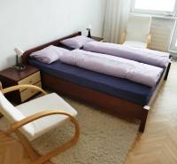 Schlafzimmer in einer 3-Zimmer-Wohnung mit einem Doppelbett, bequemen Stühlen und einem hellen Teppich.