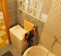 Badezimmer in einer 3-Zimmer-Wohnung mit Waschmaschine, Badewanne und Mosaikfliesenwand.