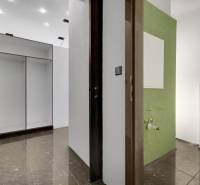 Flur mit Fliesen und Einbauschrank, der zu einem Badezimmer in Geschäftsräumen führt.