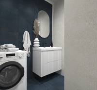 Badezimmer mit Waschmaschine, Waschbecken und dunklen Fliesen in einer 2-Zimmer-Wohnung.