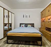 Schlafzimmer in einer 2-Zimmer-Wohnung mit Doppelbett, Einbauschrank und Holzwandmöbel.