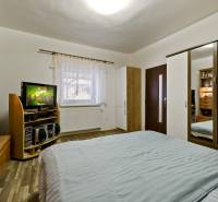 Schlafzimmer in einer 2-Zimmer-Wohnung mit Bett, Kleiderschrank, Fernseher und Holzmöbeln.