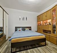 Schlafzimmer in einer 2-Zimmer-Wohnung mit Doppelbett, Schränken und dekorativem Regalsystem.