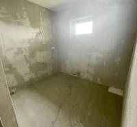 Ein Zimmer in einem Einfamilienhaus mit nackten Wänden, ein kleines Fenster, eine Lichtquelle ohne Kronleuchter.