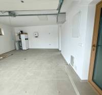Eine Garage in einem Einfamilienhaus mit weißen Wänden und großen, hellen Fliesen.