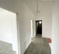 Ein Flur in einem Einfamilienhaus mit weißen Wänden und Betonboden.